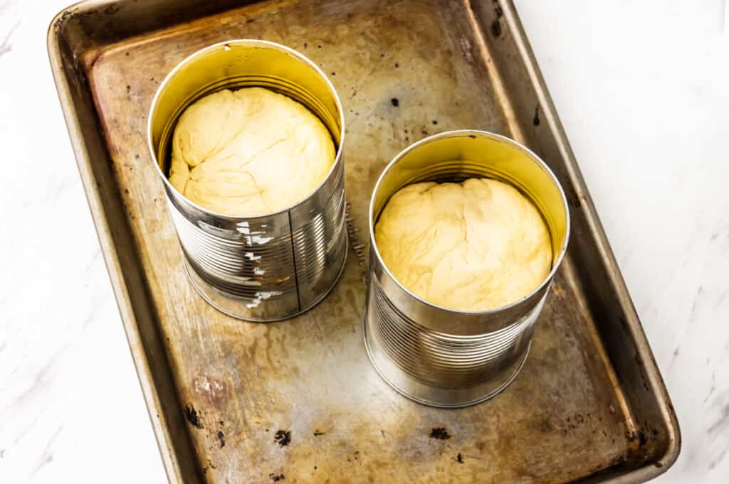 putting the dough in bread cans 