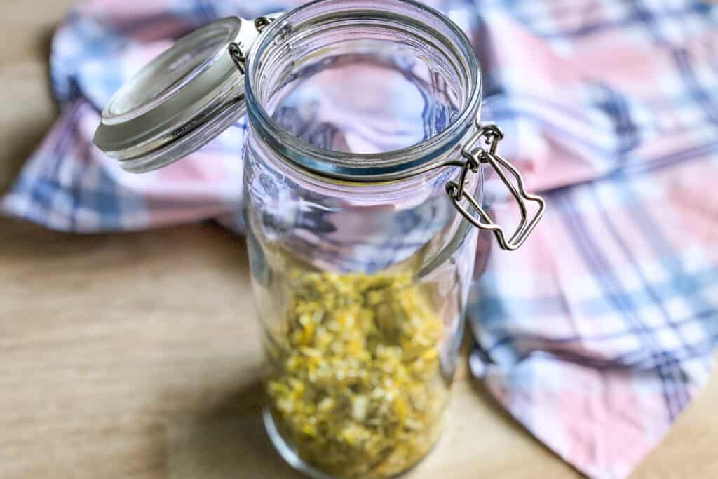 adding the dandelions to a large jar 