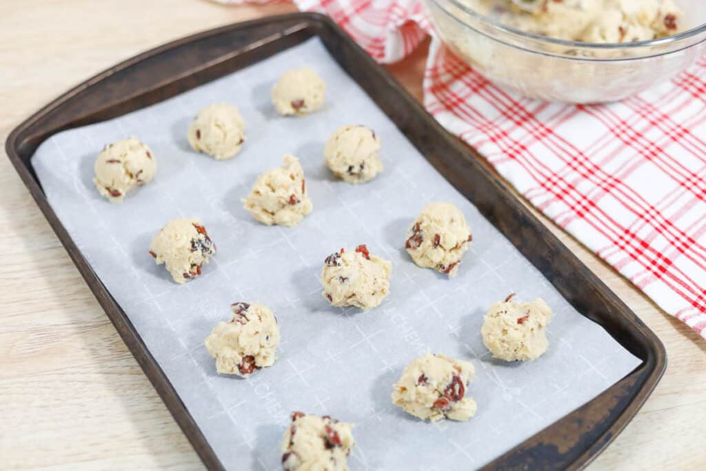 adding the cookie dough balls to the baking sheet